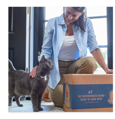 une femme avec son chat au pelage noir et un emballage d'aliments pour chats Hill's Pet